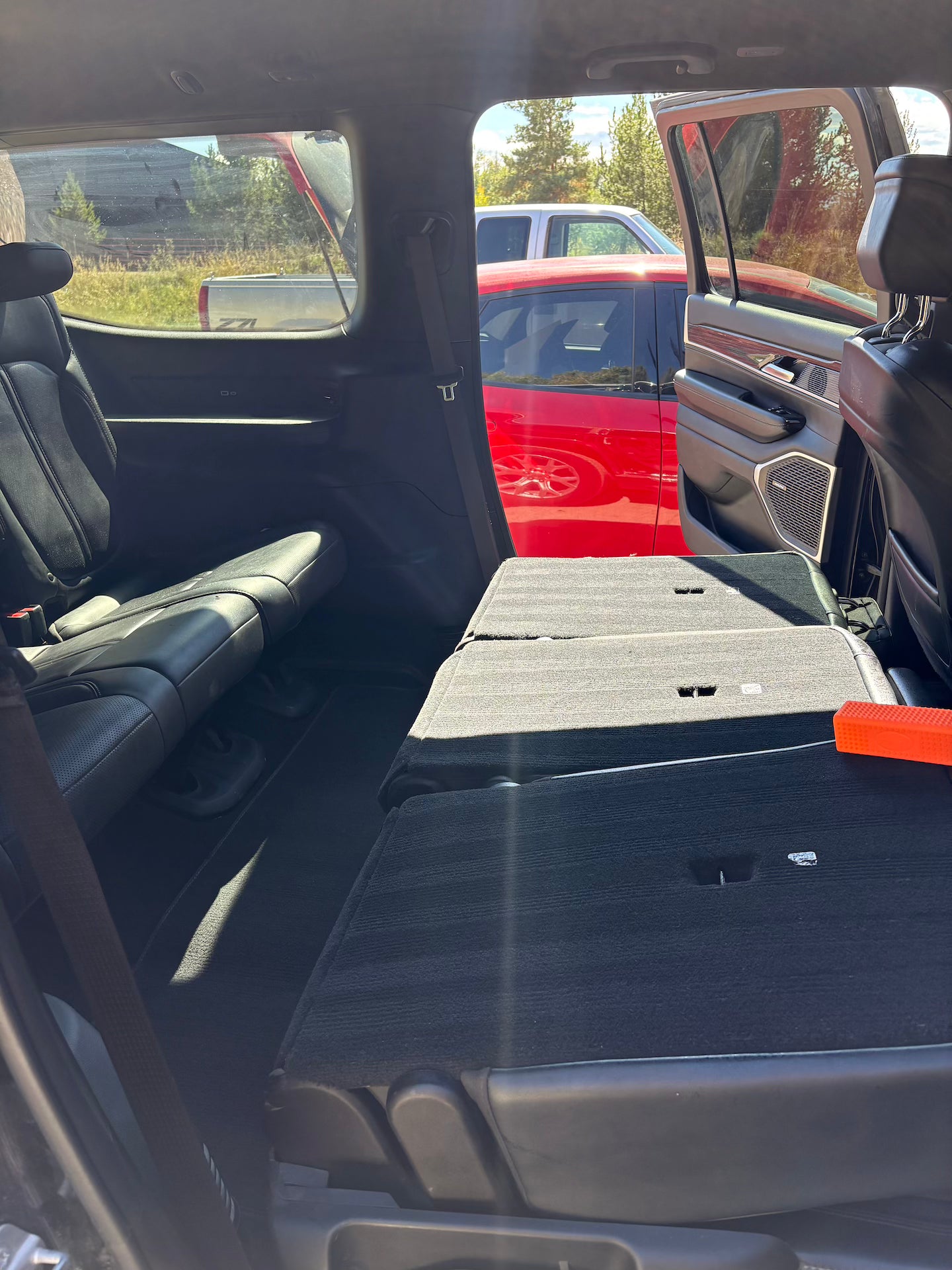 Open car trunk with a red vehicle in the background