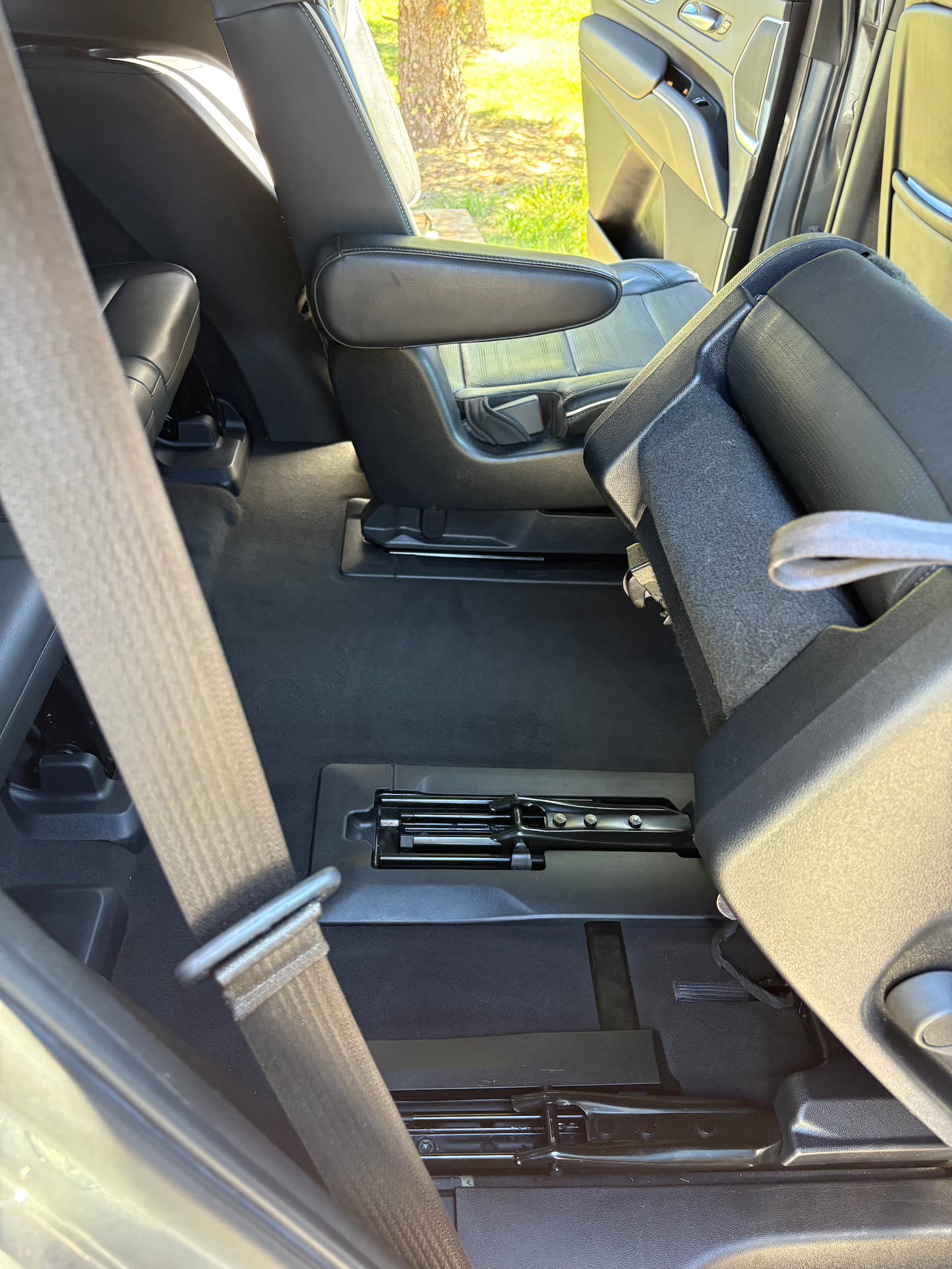 Car interior with folded seat and open door showing grass outside