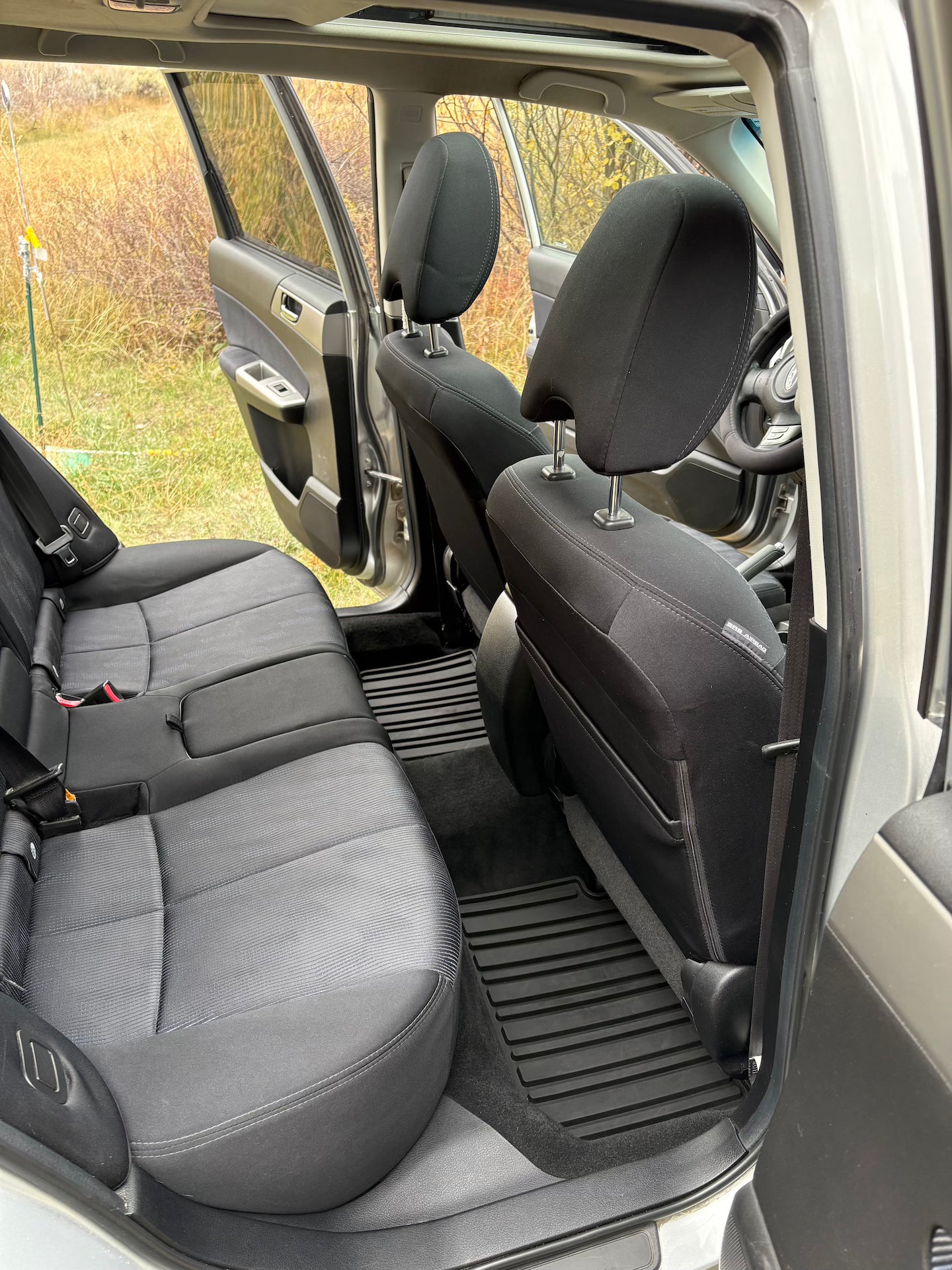 Interior of a vehicle with gray seats and open door showing grass outside