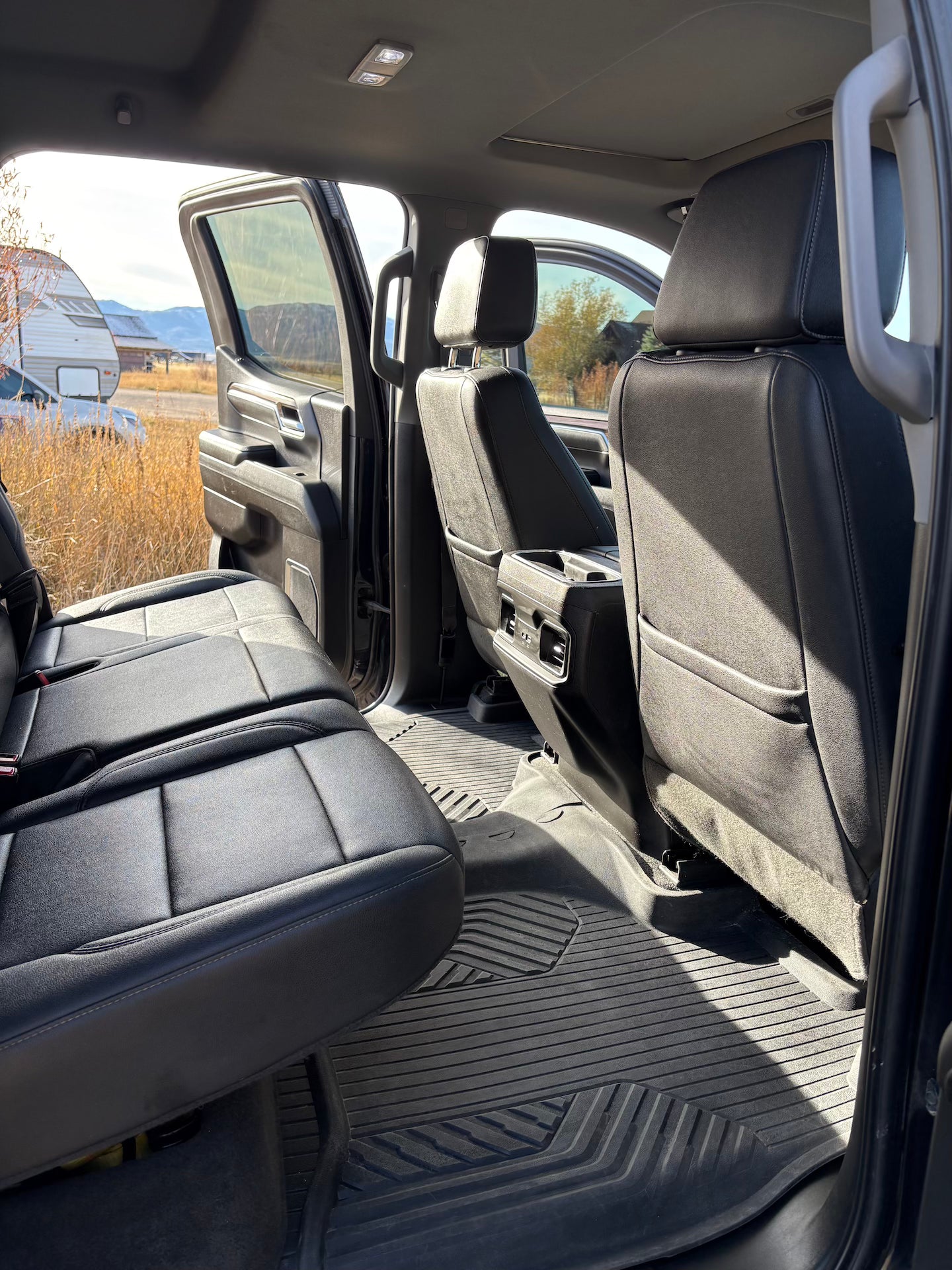 Interior of a vehicle with black leather seats and open door showing outdoor scenery.