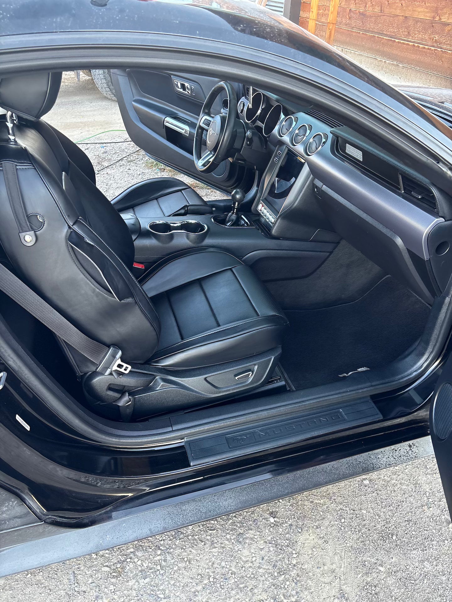 Car interior with open door showing dashboard and seats.