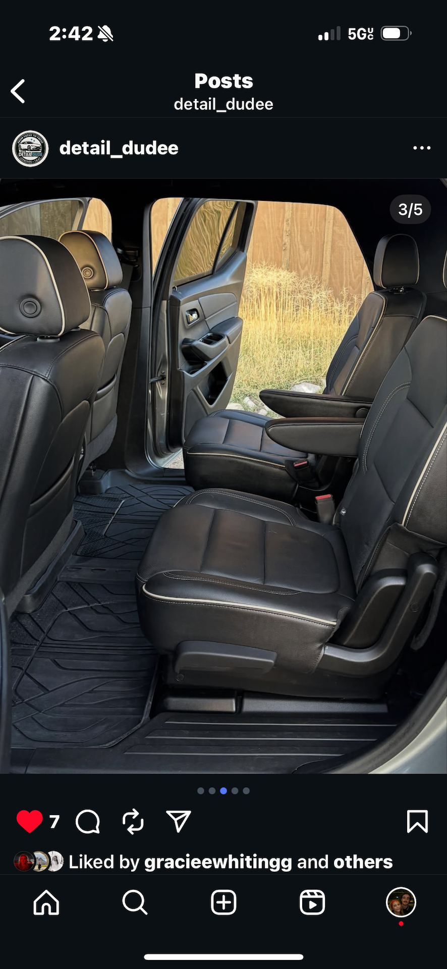 Interior of a vehicle with gray seats and open door, showing grass outside.
