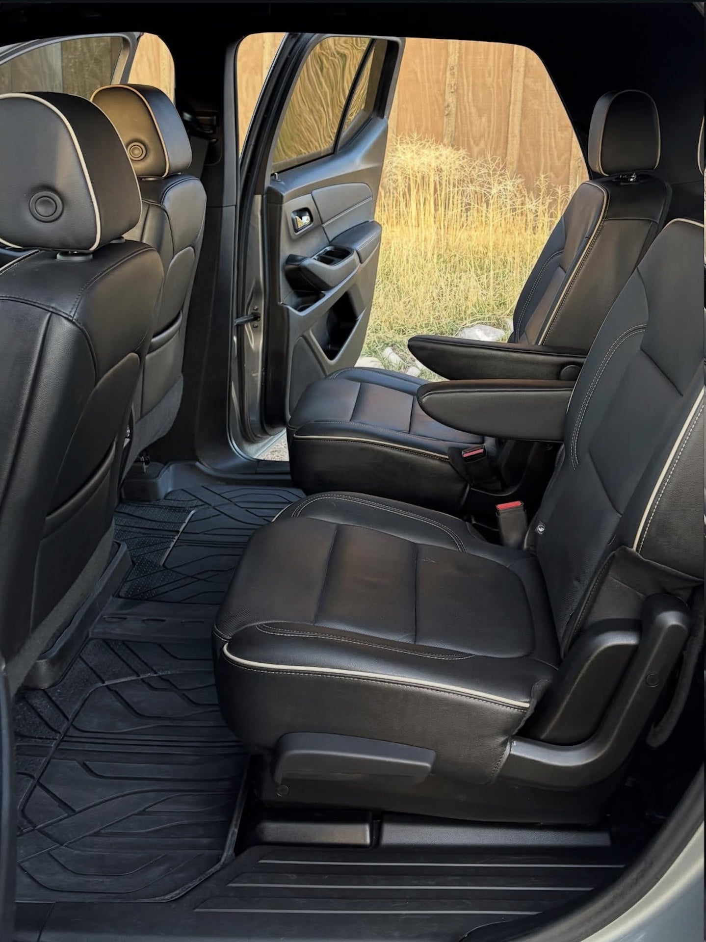 Interior of a vehicle with black leather seats and a view of the outdoors through the windows.