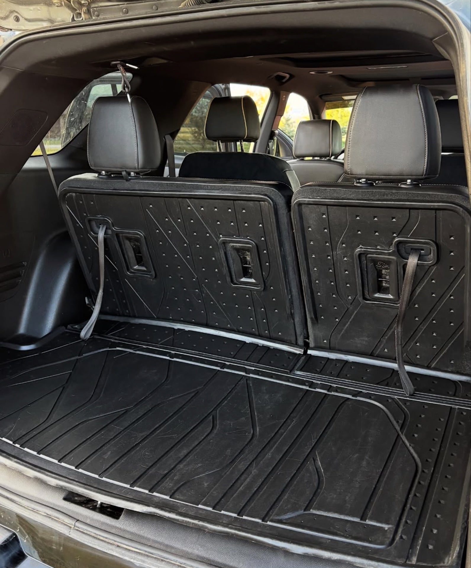 Car trunk with a black cargo liner and folded seats.