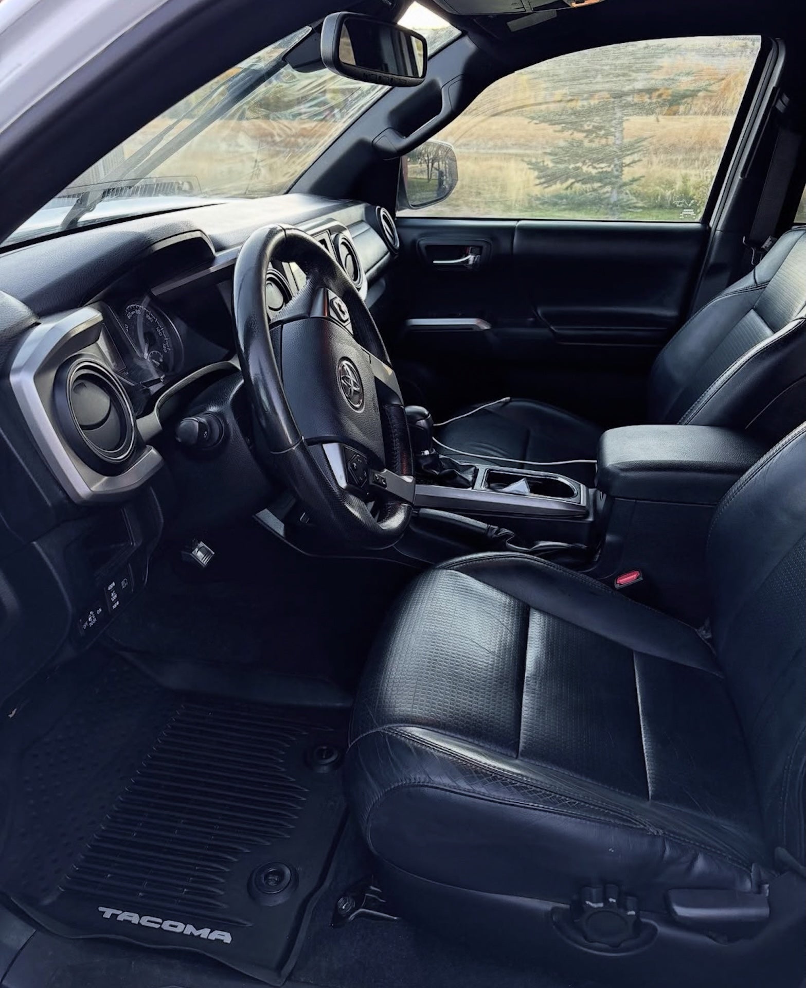 Interior of a Toyota Tacoma truck with steering wheel and dashboard.
